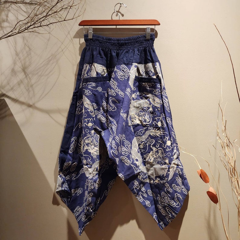 May include: Blue and white patterned pants with a wide leg and an elastic waistband. The pants have a dragon design and are made of a lightweight fabric.