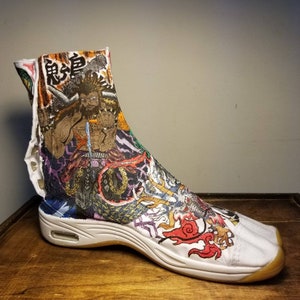 May include: White high-top shoes with a colorful, hand-painted design featuring a Japanese character, a warrior, and a dragon. The shoes have a thick, white sole.