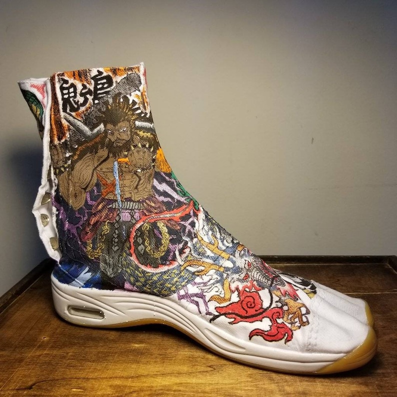 May include: White high-top shoes with a colorful, hand-painted design featuring a Japanese character, a warrior, and a dragon. The shoes have a thick, white sole.