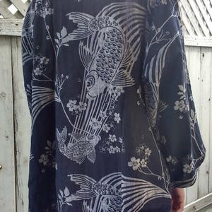 May include: A black kimono with a white floral and fish design. The kimono has long sleeves and a loose fit.