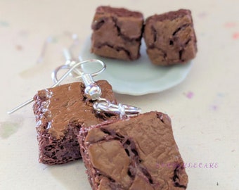 May include: A pair of earrings featuring miniature chocolate brownies with a realistic texture. The earrings are made of polymer clay and have silver hooks.