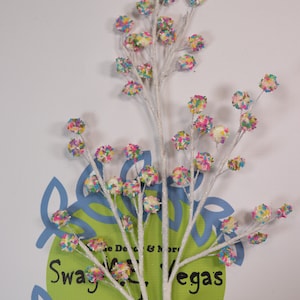 May include: White twig spray with multiple small white balls covered in colorful sprinkles. The twig spray is perfect for adding a festive touch to any home decor.