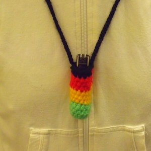 May include: A black cord necklace with a crocheted multi-coloured pouch attached. The pouch is red, yellow, green, and black.