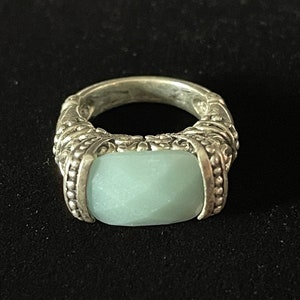 May include: A silver ring with a light blue gemstone set in a textured band.