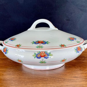 May include: White porcelain serving dish with a lid. The dish has a red and gold trim and a floral design with red, blue, and green flowers.