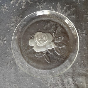 May include: A clear glass serving plate with a raised, frosted design of a single rose.