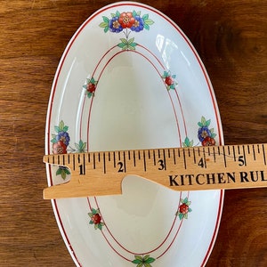 May include: White oval serving dish with a red and green floral design. The dish is 5 inches long.