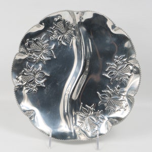 May include: A silver serving dish with a scalloped edge and floral designs. The dish is divided into two sections.