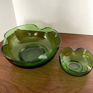 May include: Two green glass bowls with wavy edges. The larger bowl is wider and shallower than the smaller bowl.