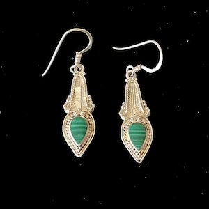 May include: A pair of silver dangle earrings with green malachite stones. The earrings have a delicate, ornate design.
