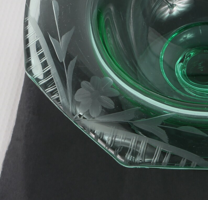 May include: A green glass bowl with an etched floral design. The bowl has a scalloped edge and is made of clear glass.
