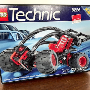 May include: LEGO Technic 8226 building set featuring a red and black construction vehicle with articulated arms and large wheels. The box shows the vehicle on a blue and white background with the text "LEGO Technic" and "8226" printed on the front. The box also includes the text "Cont. 120 pcs/pzs".