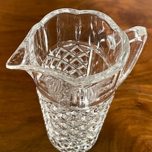 Op de afbeelding: Een glazen kan met een diamantpatroon. De kan heeft een handvat en een brede opening.