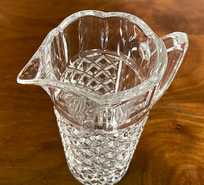 Op de afbeelding: Een glazen kan met een diamantpatroon. De kan heeft een handvat en een brede opening.