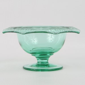 May include: A green glass pedestal bowl with a scalloped rim and a decorative etched design.