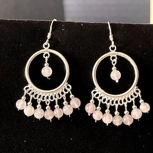 May include: Silver hoop earrings with a dangling chain of pink rose quartz beads.