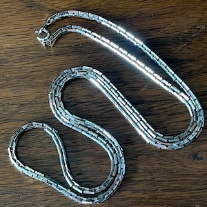 Cadena plateada de eslabones rectangulares con esquinas afiladas, años 70, 61 cm de largo, extremadamente brillante, cierre de reasa, en excelente estado.