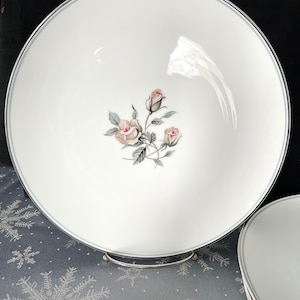 May include: A white ceramic bowl with a silver rim and a floral design featuring three pink roses with green leaves.
