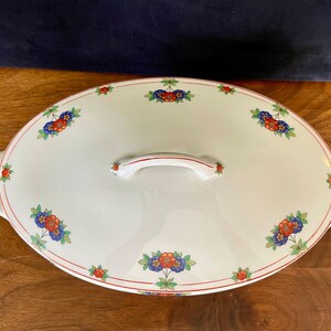 May include: White oval serving dish with a floral design in red, blue, and green. The dish has two handles and a lid with a handle.