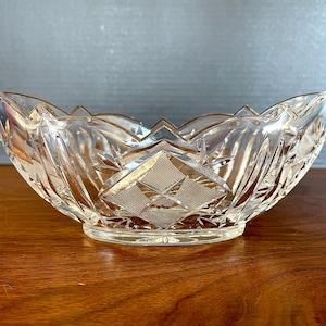 May include: A clear glass bowl with a cut-glass design. The bowl has a scalloped edge and a diamond-shaped pattern in the center.