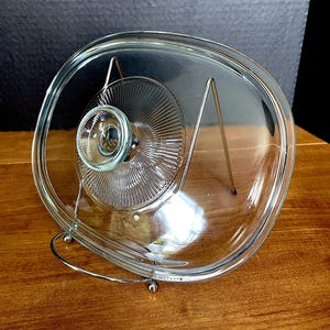 Tapa de vidrio rectangular Pyrex con pomo y esquinas redondeadas, con diseño de rayos de sol acanalados en el centro alrededor del pomo. 25 Pyrex F 12 C de canto, poco uso, sin daños.