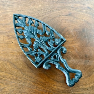 May include: A black cast iron trivet shaped like an old-fashioned iron with a decorative floral design.