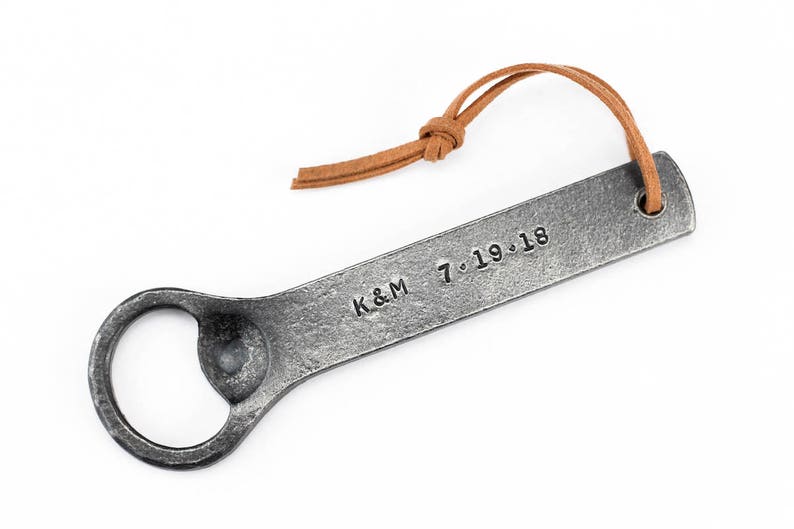 Customized hand forged iron bottle opener with a leather tassel on a white background.