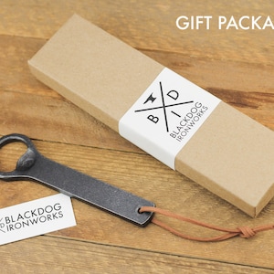 Our gift packaging option which consists of a kraft colored box that is long and rectangular and a white closure, printed with the Black Dog Ironworks logo.