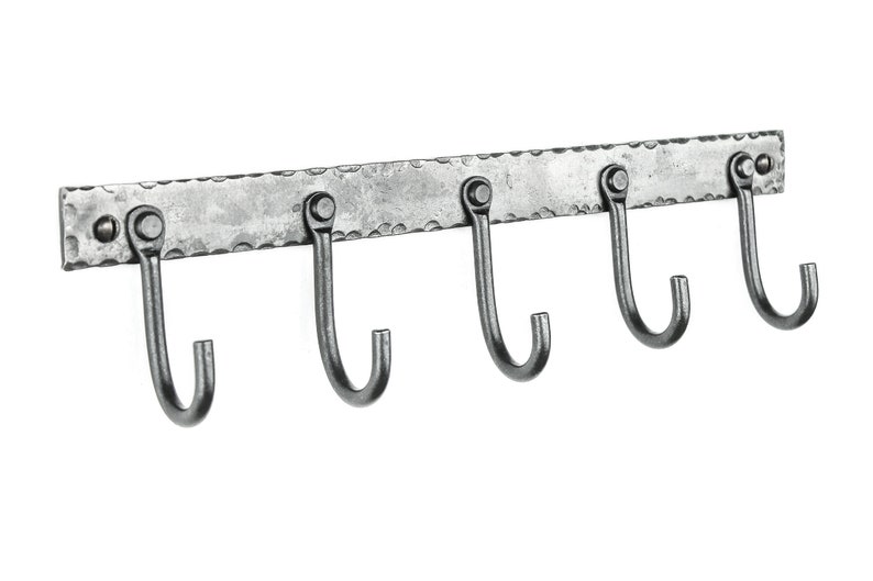 May include: A silver metal wall-mounted hook rack with five hooks. The rack has a hammered finish and is designed for hanging items.