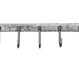 May include: A silver metal hook rack with five hooks. The rack has a hammered texture and is mounted on a wall.