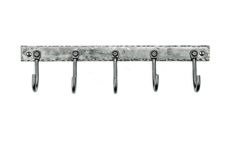 May include: A silver metal hook rack with five hooks. The rack has a hammered texture and is mounted on a wall.