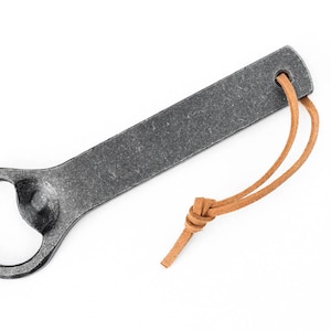 A gray hand forged iron bottle opener on a white background.