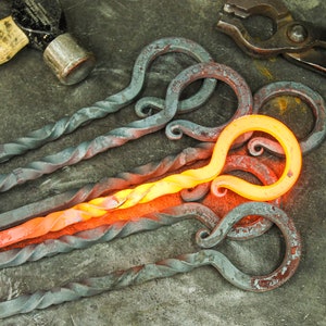 Hand forged iron fire poker twisted handles on a rustic metal table.