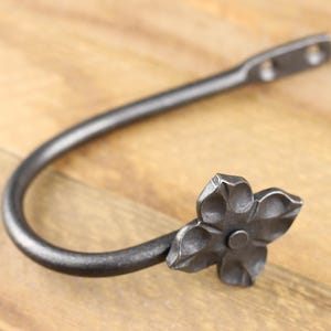 Handmade iron curtain hold back hook, Flower style, on a rustic background.