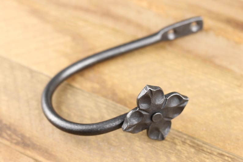 Handmade iron curtain hold back hook, Flower style, on a rustic background.