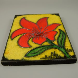 Könnte beinhalten: Eine rote Blume mit grünen Blättern auf gelbem Hintergrund. Die Blume ist stilisiert und hat einen schwarzen Umriss. Die Fliese ist schwarz gerahmt.