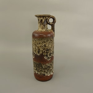 May include: A brown ceramic vase with a white and black glaze pattern. The vase has a narrow neck and a single handle.