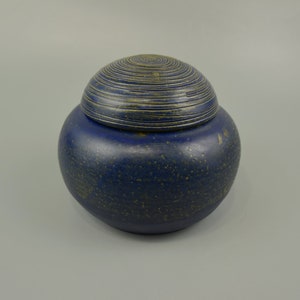 May include: A blue ceramic jar with a lid. The jar has a speckled finish and the lid has a concentric circle design.