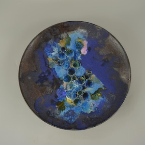 Könnte beinhalten: Ein blauer und brauner Keramikteller mit einem Design aus blauen und grünen Kreisen in einer Gruppe.