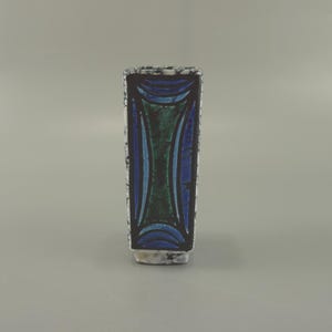 May include: A rectangular ceramic vase with a textured surface. The vase features a central design of blue and green curved shapes, framed by a dark border. The vase is approximately 6 inches tall.