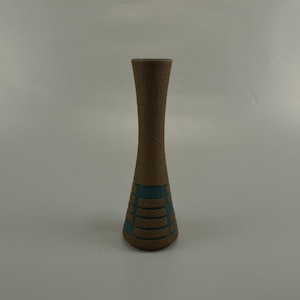 Könnte beinhalten: Eine braune Keramikvase mit einem blauen geometrischen Muster. Die Vase hat einen schmalen Hals und einen breiten Boden.