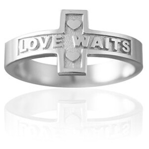 May include: A silver ring with a cross design and the words "LOVE WAITS" engraved on the band. Two small hearts are engraved on the cross.