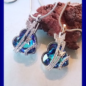 Peut inclure: Deux colliers en argent avec des pendentifs en forme de cœur en cristal bleu. Chaque pendentif présente un délicat motif de papillon avec des accents de cristal transparent.
