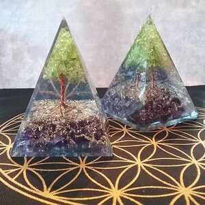 May include: Two clear glass pyramids with copper wire tree sculptures inside. The pyramids are filled with green and purple crystals.