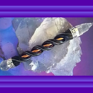 May include: A black and brown twisted wooden wand with clear quartz crystal tips and silver accents.