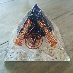 May include: A clear crystal pyramid with a black obsidian point and copper wire spirals inside. The pyramid is filled with clear quartz crystals.