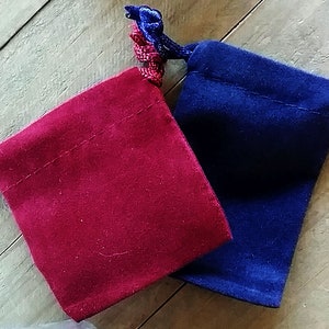 May include: Two small velvet drawstring bags, one red and one blue, with matching cords.