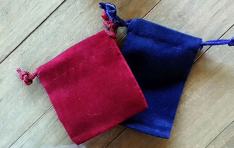 May include: Two small velvet drawstring bags, one red and one blue, with matching cords.