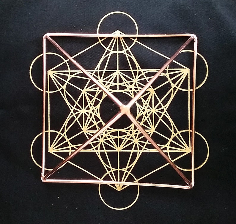 K&ouml;nnte beinhalten: Eine geometrische Form aus Kupferdraht mit einem goldenen Design im Inneren. Die Form ist ein W&uuml;rfel mit einer Pyramide auf der Oberseite. Das Design im Inneren ist ein komplexes Muster aus Kreisen und Linien.