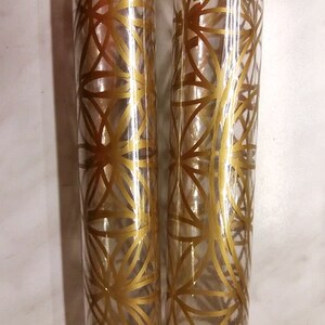 May include: Two clear glass tubes with a gold geometric pattern design.